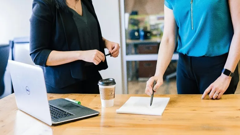 duas pessoas em uma empresa conversando ao lado de uma mesa com um computador, avaliação de competências