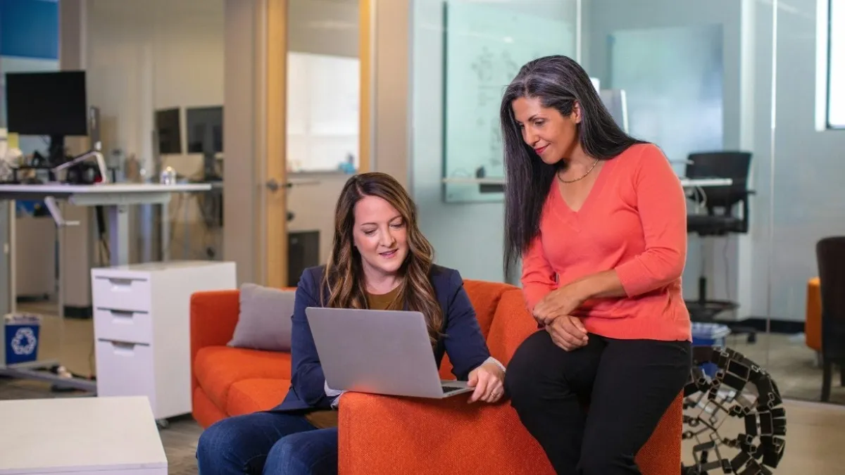 duas mulheres olhando para um notebook e conversando em uma empresa, avaliação de desempenho