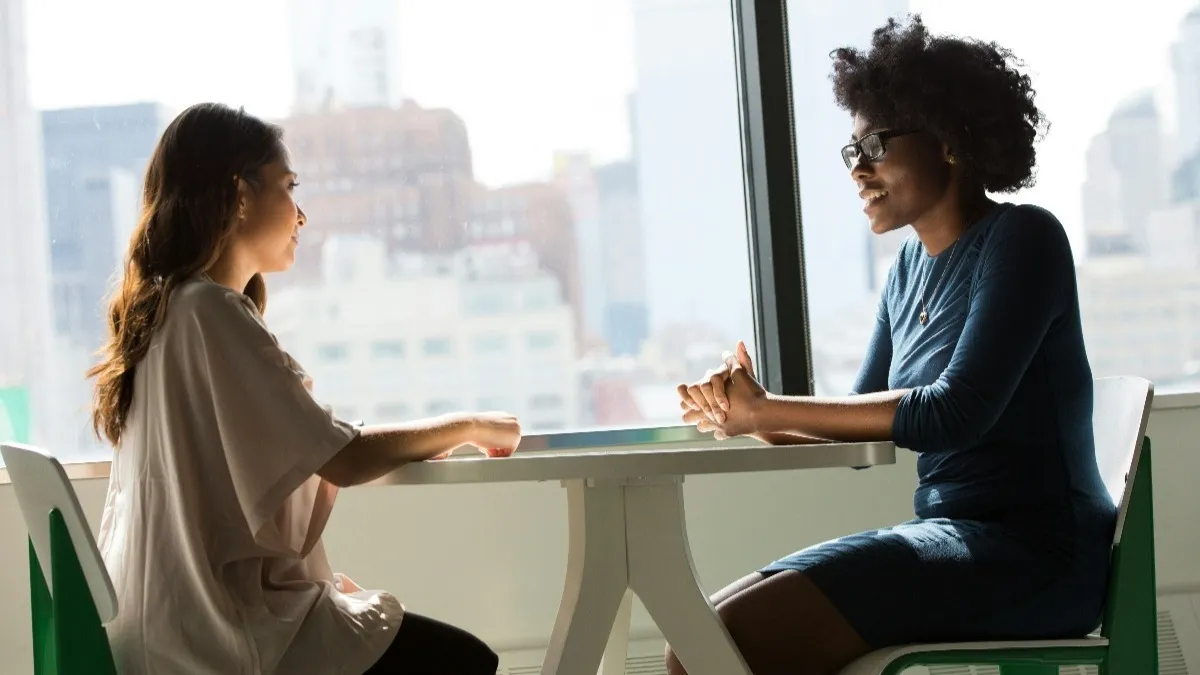 duas mulheres conversando frente a frente em uma mesa, num ambiente corporativo, mapeamento de competências