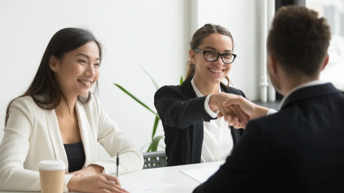 duas mulheres conversando com um homem durante entrevista de emprego, recrutamento e seleção