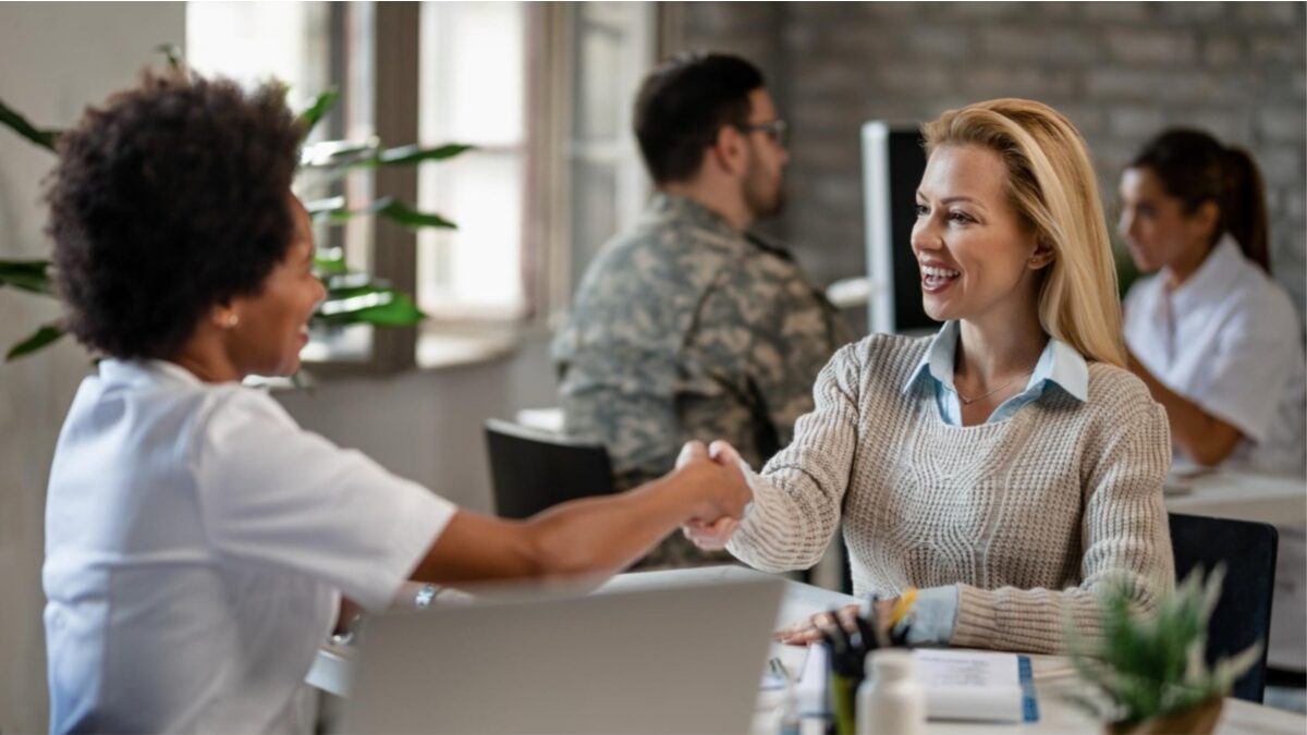 aperto de mão entre duas mulheres em um ambiente de empresa, benefícios corporativos