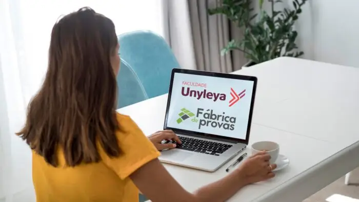 mulher mexendo no computador e a tela tem os logotipos de unyleya e fábrica de provas