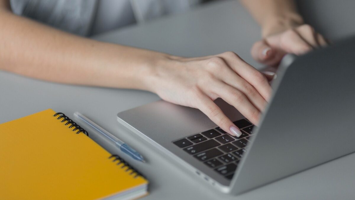 mulher mexendo no computador com um caderno e caneta ao lado, plataforma de avaliações