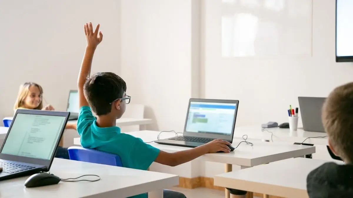 menino de óculos levantando a mão para responder durante a aula com notebook, ensino híbrido