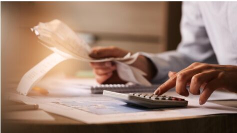 pessoa com calculadora em ambiente escolar, como reduzir custos na escola