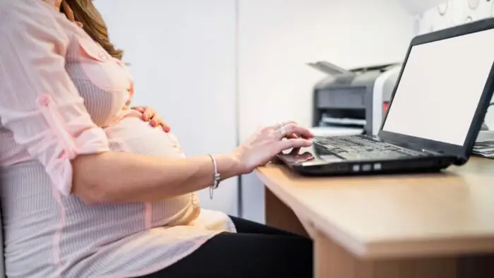 mulher grávida mexendo no computador, licença maternidade