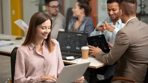 mulher mexendo no notebook em ambiente corporativo com mais pessoas, tecnologia no rh